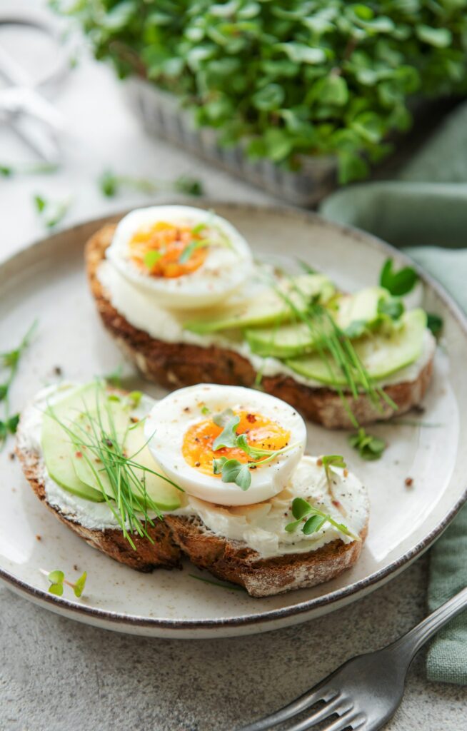 Bread toast, boiled eggs, avocado slice, microgreens on a plate