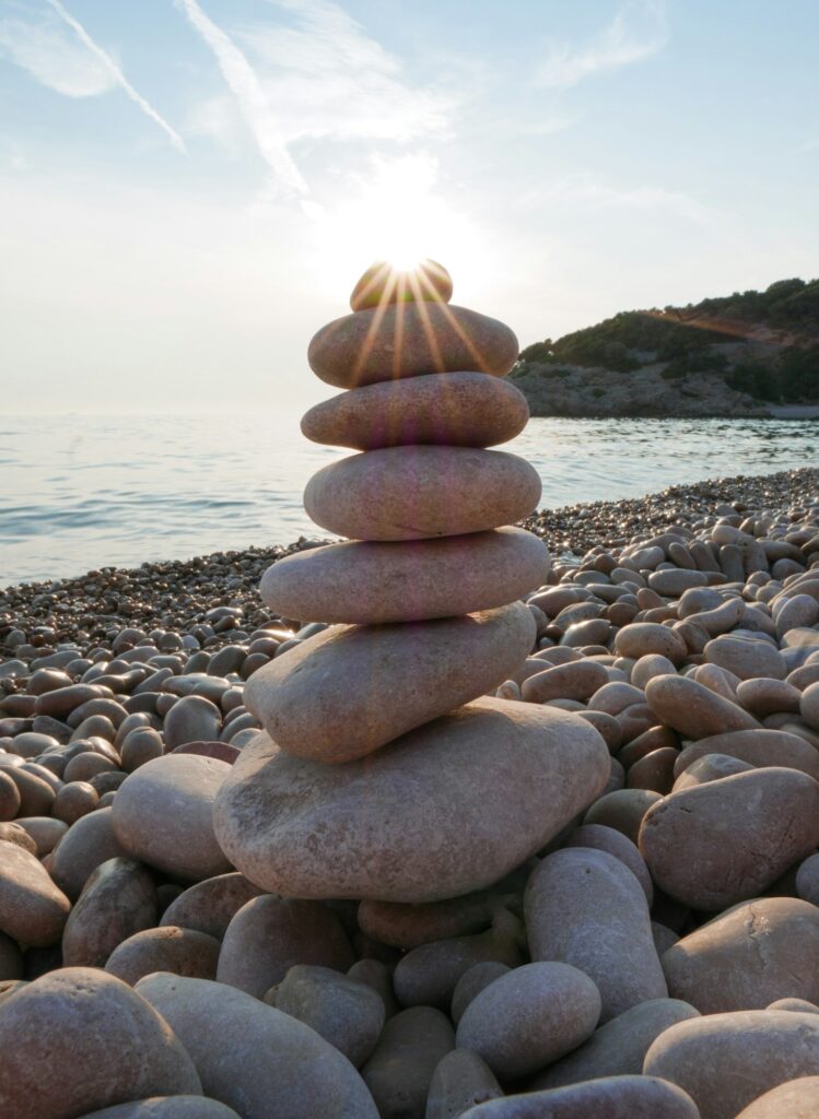 Close-up of stacked stones on beach. Natural light, zen, sea, sunburst.